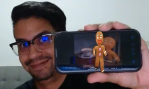 ingcarlosreina mostrando su telefono como marcador de realidad aumentada para una app que muestra un video sin fondo